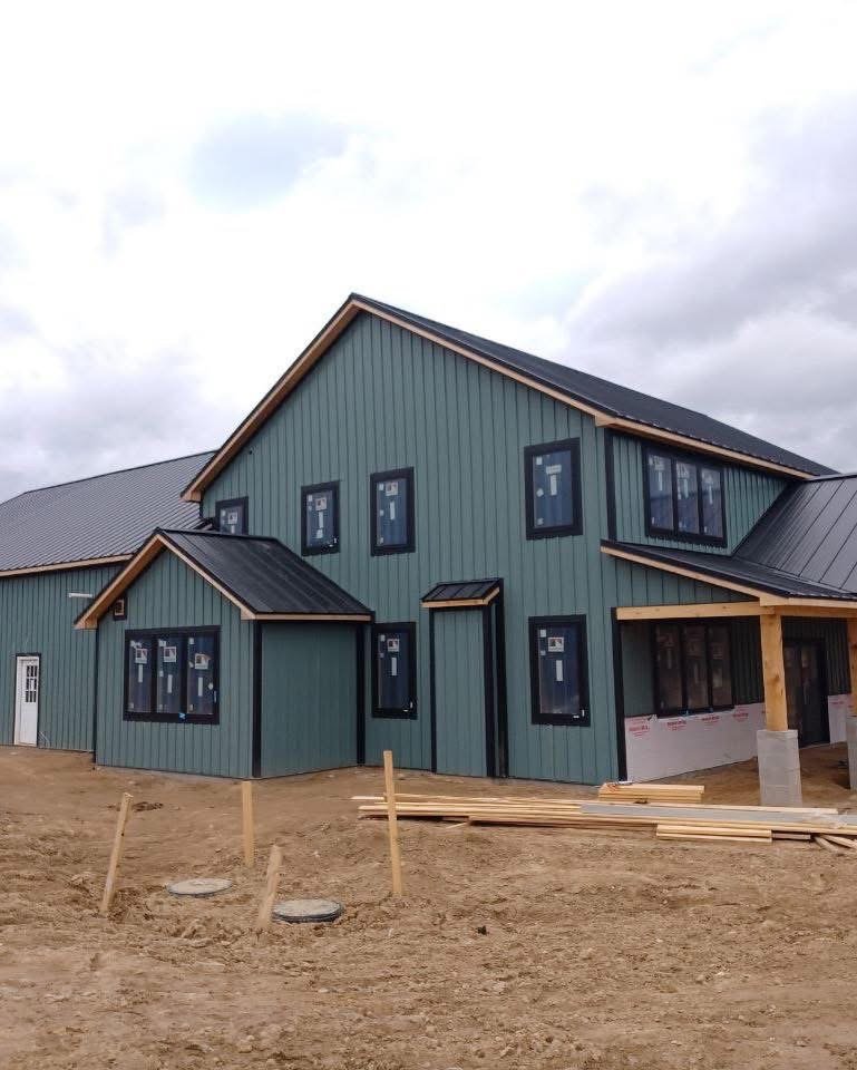 Slate-green modern farmhouse with a Windy Hill metal roof and timber porch
